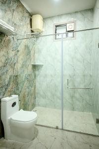 een badkamer met een toilet en een glazen douche bij hotel ustav in Bolpur