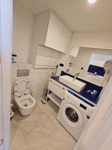 een badkamer met een toilet, een wastafel en een wasmachine bij Sea View Lux Aparthotel in ORBi City Batumi in Batoemi