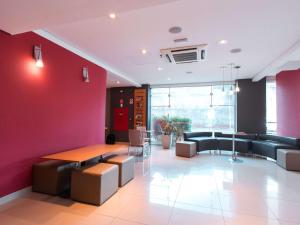 a waiting room with a red wall and tables and chairs at ibis Presidente Prudente Manoel Goulart in Presidente Prudente