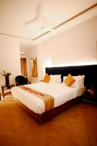 een slaapkamer met een groot wit bed met oranje kussens bij hotel ustav in Bolpur
