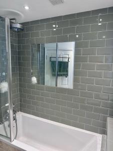 y baño con bañera blanca y espejo. en Large Bedroom in beautiful house, en Londres