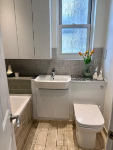 baño con lavabo y aseo y ventana en Large Bedroom in beautiful house, en Londres