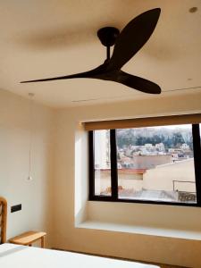 un ventilatore a soffitto in una camera da letto con finestra di Athens Tower Hotel by Palladian Hotels ad Atene