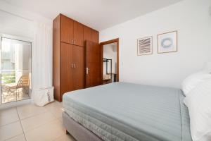 1 dormitorio con 1 cama, armarios de madera y balcón en Gaia 4 - 5 min to Beach, en Cos