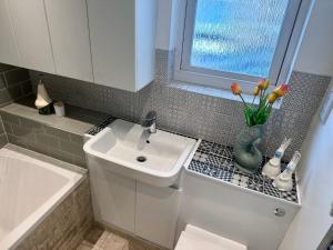ein Badezimmer mit einem Waschbecken und einer Vase aus Blumen in der Unterkunft Large Bedroom in beautiful house in London