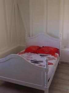 Una cama blanca con almohadas rojas en un dormitorio en Villa QUIETUDE, en Sainte-Anne