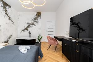 Schlafzimmer mit einem Bett, einem Schreibtisch und einem TV in der Unterkunft Luxury apartment with a sauna and bedroom with bath in Krakau