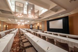 un salón de banquetes con mesas y sillas blancas y una pantalla en Hotel Maya - a DoubleTree by Hilton Hotel, en Long Beach