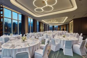 a ballroom with white tables and chairs and large windows at Hilton Sofia in Sofia