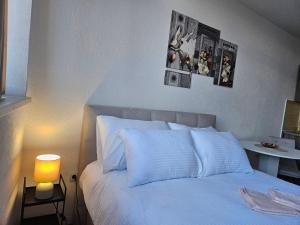 ein Schlafzimmer mit einem weißen Bett und einem Tisch mit einer Lampe in der Unterkunft Mrakovica 1 in Prijedor