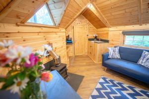 a living room with a blue couch in a wooden cabin at Chestnut Tree House with Hot tub & Sauna in Barmouth