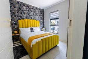 a bed with a yellow headboard in a room at Central Serenity @Midrand in Midrand