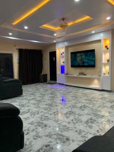 ein Wohnzimmer mit einem TV und Marmorböden in der Unterkunft Umbrella properties - Eleyele Ibadan in Ibadan