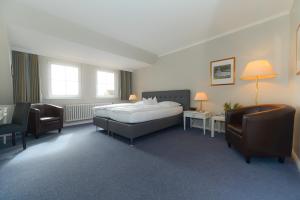 - une chambre avec un lit, un bureau et des chaises dans l'établissement Kurhaus Hotel, à Wyk auf Föhr