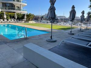 a pool with umbrellas and chairs next to a building at Gulmarn 201 in Cape Town