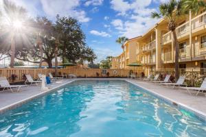 - une piscine dans un complexe avec des chaises et un bâtiment dans l'établissement La Quinta Inn by Wyndham Orlando Airport West, à Orlando