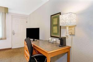 a room with a desk with a television and a lamp at La Quinta Inn by Wyndham Orlando Airport West in Orlando