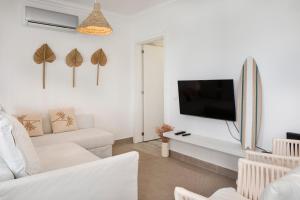 a living room with a white couch and a tv at TAC - Sagres Studio in Sagres