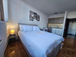 1 Schlafzimmer mit einem großen weißen Bett und einer Küche in der Unterkunft Mrakovica 1 in Prijedor