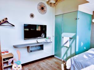 1 dormitorio con TV de pantalla plana en la pared en Xianwang Homestay en Jincheng