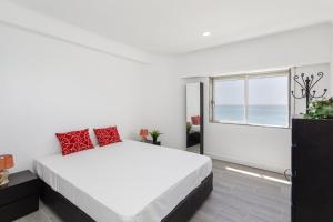 a white bedroom with a large bed and a window at Quarteira SeaViews in Quarteira