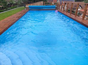 uma piscina com água azul e um deque de madeira em Völgy Villa em Zebegény