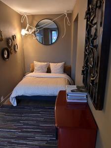 een slaapkamer met een bed met een spiegel en een tafel bij cozy in Montbéliard