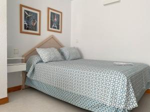 Schlafzimmer mit einem Bett mit einer blauen und weißen Bettdecke in der Unterkunft La Colina in Albir
