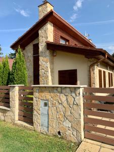 uma casa com uma parede de pedra e uma cerca em VILLA BARRACA em Dunapataj