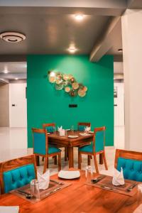 comedor con mesa, sillas y pared verde en Hiru Beach Resort en Kalpitiya