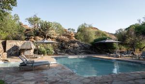 einen Pool mit 2 Stühlen und Sonnenschirmen in der Unterkunft Tuli Safari Lodge Mashatu in Lentswelemoriti