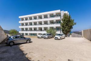 three cars parked in a parking lot in front of a building at Lito Hotel in Ixia