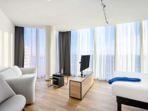 a living room with a couch and a tv and some windows at ibis Budapest Stadium in Budapest