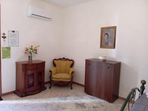 Zimmer mit einem gelben Stuhl und einem Holzschrank in der Unterkunft ELICO A Sicily in Sambuca di Sicilia