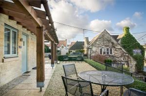 eine Terrasse mit einem Tisch und Stühlen sowie ein Gebäude in der Unterkunft The Old House At Home in Castle Combe