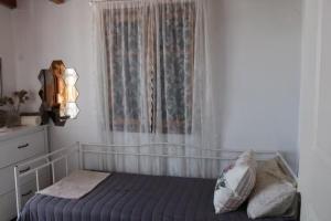 a bedroom with a bed and a window with curtains at The Light Blue House in Karavostamo