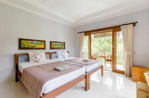 a bedroom with two beds and a balcony at Artja Inn Ubud in Ubud