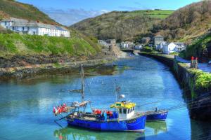 two boats are docked in a river near a town at The Riverside in Boscastle