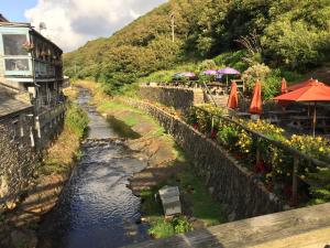 a river with tables and umbrellas next to a building at The Riverside in Boscastle