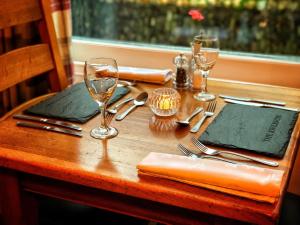 a wooden table with forks and glasses and napkins at The Riverside in Boscastle