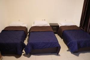 three beds are sitting in a room at Sejan hotel in Aqaba