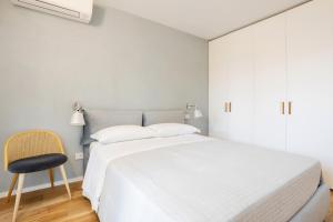 a bedroom with a white bed and a chair at Luna di mare - nuovo appartamento sul mare in Acireale