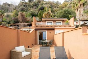a patio with a table and chairs and a house at Luna di mare - nuovo appartamento sul mare in Acireale
