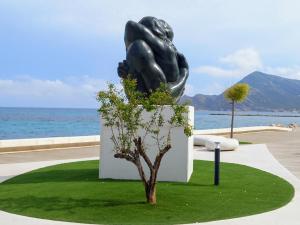 una estatua de una mujer sentada en un pedestal junto al océano en Altea Olivos G, en Altea
