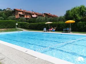 a large swimming pool with two umbrellas next to a house at Appartamento Giada in Padenghe sul Garda