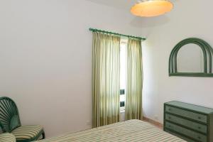a bedroom with a bed and a chair and a window at TAC - Vilamoura Center in Vilamoura