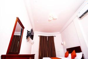1 dormitorio con 1 cama con almohadas de color naranja y espejo en Vedoko appart'hotel, en Cotonou