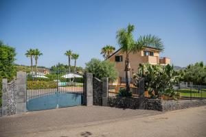 a gate in front of a house with palm trees at Villa Trinacria, Piedimonte Etneo in Presa