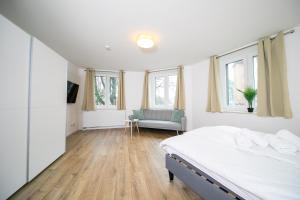 a bedroom with a bed and a couch and windows at Stylish Apartments - 71 m² - Zentral - 10 Min Messe in Düsseldorf