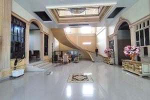 eine große Lobby mit einer Treppe und ein Zimmer mit Blumen in der Unterkunft ZAHIRA GUESTHOUSE in Paalmerah